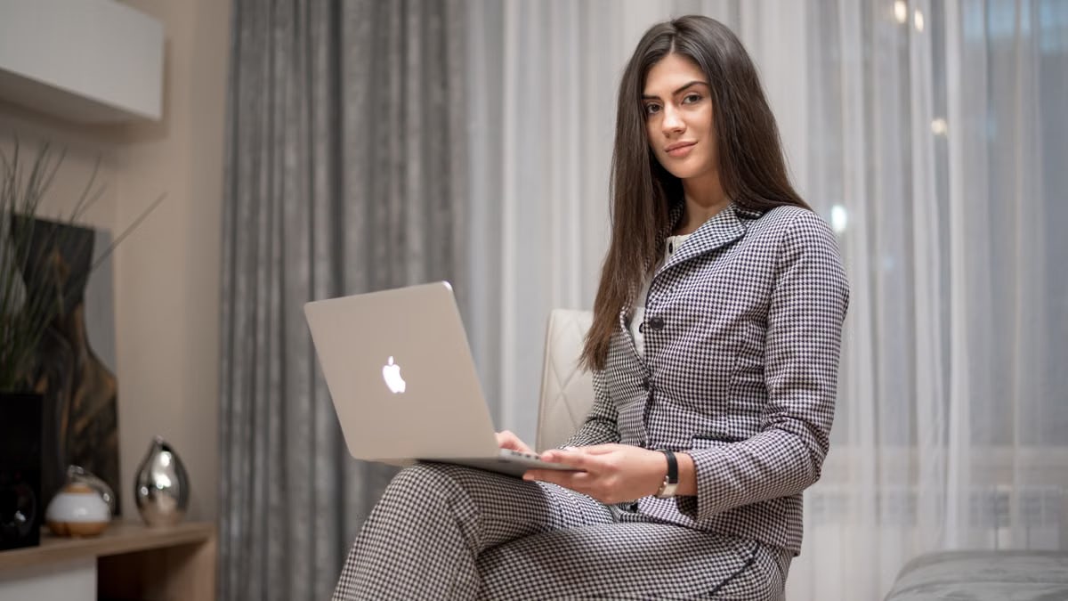 Confident woman using a laptop at home for remote work in a stylish living room.